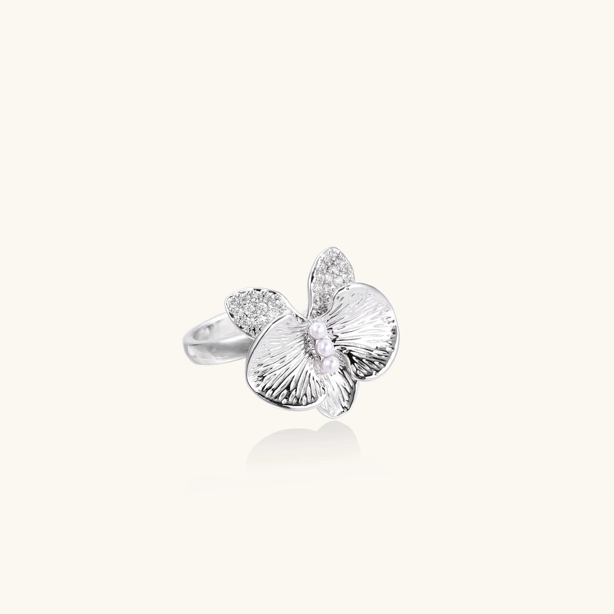 Silver-toned orchid ring with textured petals, pearl center accents, and sparkling zirconia stones on white background.